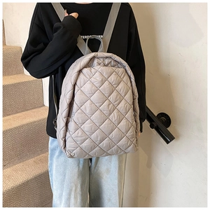 Détail du tissu en nylon matelassé gris clair et des bretelles réglables du sac à dos