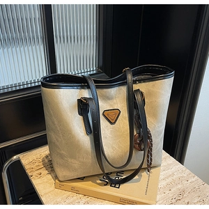 Détail du grand sac cabas gris-brun avec logo triangle en métal et décor d'anneau en bois
