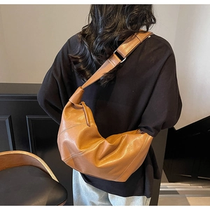 Borsa a tracolla a mezzaluna in pelle marrone su modella con finitura opaca premium