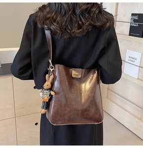 Detail of dark brown vintage wax leather bucket bag with cute plush rabbit charm