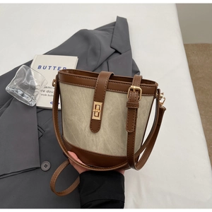Detail of retro bucket bag with brown leather trim and golden metal twist lock closure