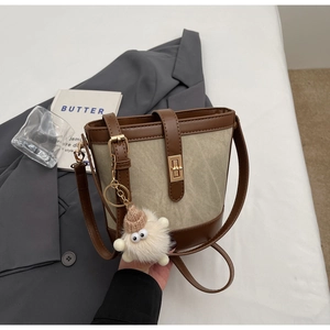 Close-up of canvas bucket bag with leather trim and a cute plush sheep pendant