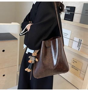 Detail of dark brown oil wax leather bucket bag with a cute rabbit charm pendant