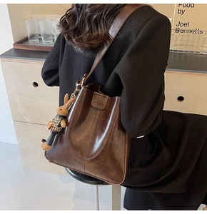 Close-up of deep brown oil wax leather tote bag with magnetic flap and bunny charm