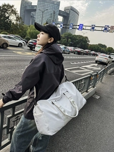 Sac de voyage blanc grande capacité avec texte 'Believe in yourself' sur fond urbain
