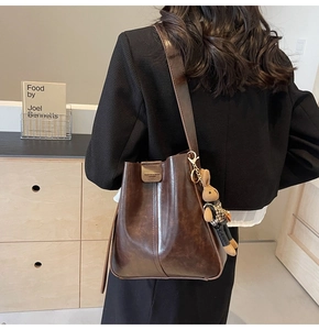 Detail of dark brown wax leather bucket bag with retro bunny charm and metal buckle