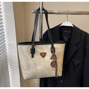 Détail du cabas vintage beige avec logo doré et pendentif tressé élégant
