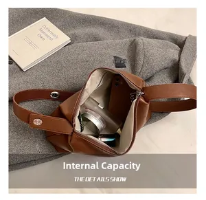 Capacité interne du sac polochon rétro en cuir marron avec cosmétiques et mobile