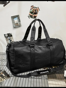 Grand sac de voyage noir en cuir avec bandoulière et slogan sur fond blanc épuré