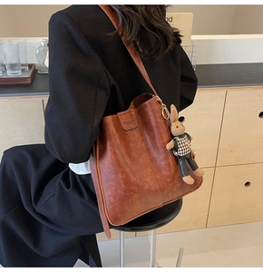 Close-up of retro brown leather shoulder bag with cute knit rabbit doll pendant