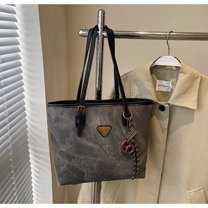 Détail du sac cabas rétro gris avec lanières en cuir et pendentif décoratif en bois
