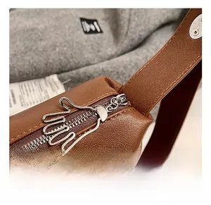 Détails de la fermeture éclair argentée créative sur un sac en cuir marron à grain litchi
