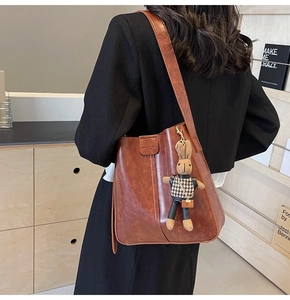 Detail of reddish-brown bucket bag with a cute rabbit pendant and soft vintage texture
