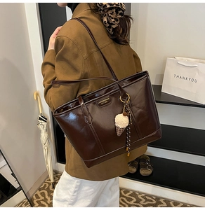 Détail d'un sac cabas marron foncé brillant avec charm glace et plaque métallique
