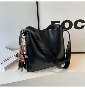 Detail of black PU leather bucket bag with a stylish houndstooth bunny charm accessory