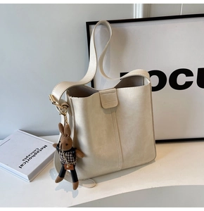 Detail of cream bucket bag with magnetic closure and cute brown bunny plush charm