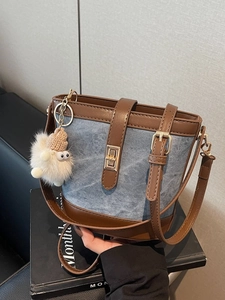 Blue denim bucket bag with brown leather trim and cute white plush charm on books