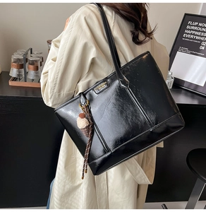 Détail du sac cabas en cuir verni noir brillant avec breloque peluche et cordon tressé