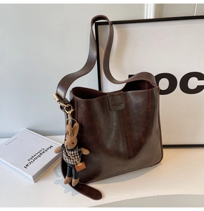 Detail of vintage brown PU leather bucket bag with retro texture and cute rabbit charm