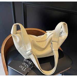 Detail of cream leather shoulder bag showing pebbled texture and silver buckle