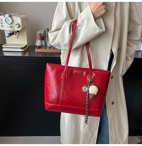 Détail d'un cabas en cuir rouge brillant avec logo doré et charm de sac crème glacée