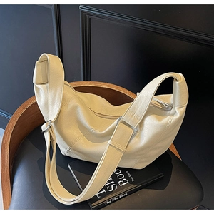 Macro shot of cream-white crescent bag featuring lychee texture and silver buckle
