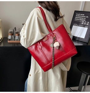 Détail du grand sac cabas rouge brillant avec étiquette dorée et breloque peluche