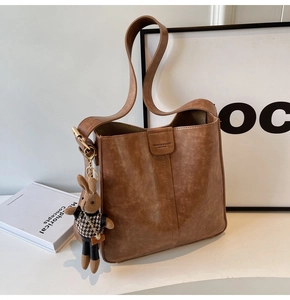Detail of brown faux leather tote bag with embossed logo and cute rabbit charm