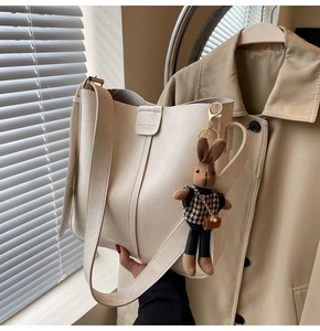 Detail of cream leather bucket bag featuring a cute bunny pendant and branded engraving