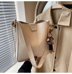 Detail of cream leather tote bag with vertical stitching and cute knit bunny charm
