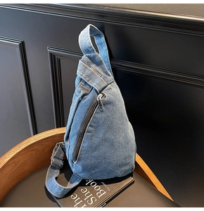 Detail of blue denim crossbody chest bag with vintage wash and adjustable strap