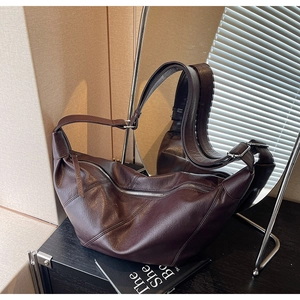 Close-up of retro dark brown leather crescent bag with silver zipper and buckle