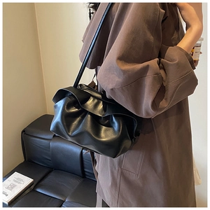 Vue détaillée du sac nuage plissé noir montrant la texture et la bandoulière sur un modèle