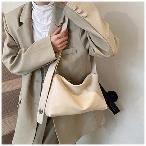 Détail d'un sac hobo blanc crème avec bandoulière large et œillets décoratifs argentés