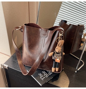 Detail of dark brown leather bucket bag featuring fashion embossing and a cute bunny charm