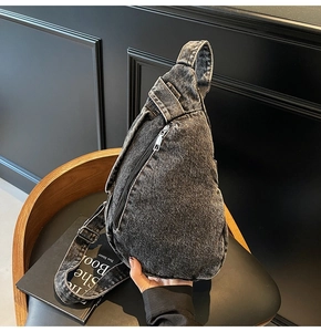 Close-up of washed denim crossbody bag featuring a vertical silver zipper and wide strap
