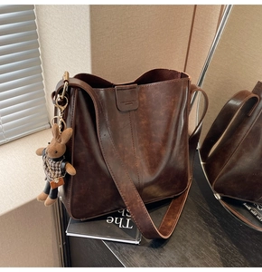 Detail of dark brown leather tote with vintage texture and cute bunny plush charm