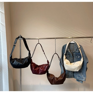 Detail of minimalist pleated half-moon bags in black, burgundy, coffee, and beige colors