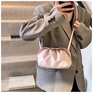 Gros plan du sac nuage rose plissé avec fine bandoulière sur une tenue de blazer gris