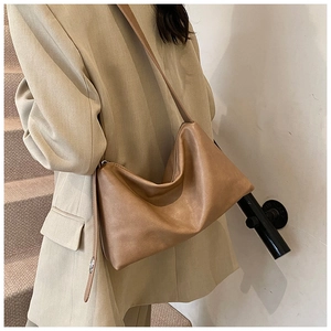 Sac bandoulière en similicuir marron en forme de demi-lune porté par un modèle