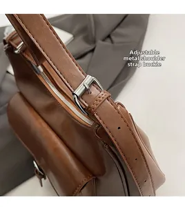 Detail of adjustable shoulder strap with silver buckle on brown leather underarm bag
