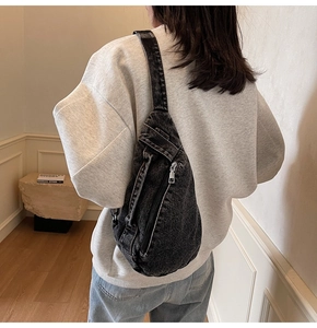 Detail view of a vintage wash denim sling bag showing its capacity and fit on a person