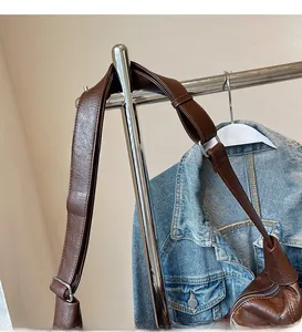 Detail of smooth wide adjustable shoulder strap with silver buckle on brown crossbody bag