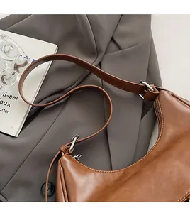 Detailed close-up of brown leather crescent bag with adjustable strap and silver buckle