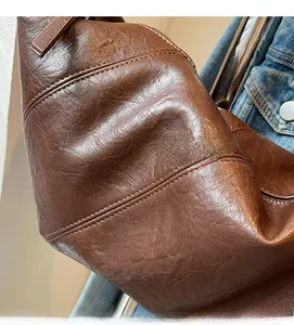 Detailed macro view of dark brown leather texture and stitching on the crossbody bag