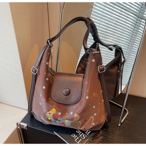 Close-up of brown polka dot shoulder bag featuring cute dog embroidery and snap closure