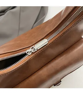 Close-up of smooth metal zipper and vintage brown leather texture on shoulder bag