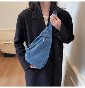 Detail of blue denim crossbody bag featuring metal zipper and wide adjustable strap