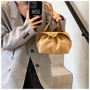 Détail d'un sac nuage plissé beige tenu par un mannequin montrant la texture du cuir PU