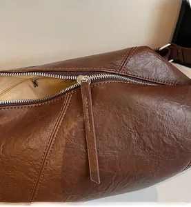 Close-up of smooth metal zipper and textured brown leather on a vintage crossbody bag